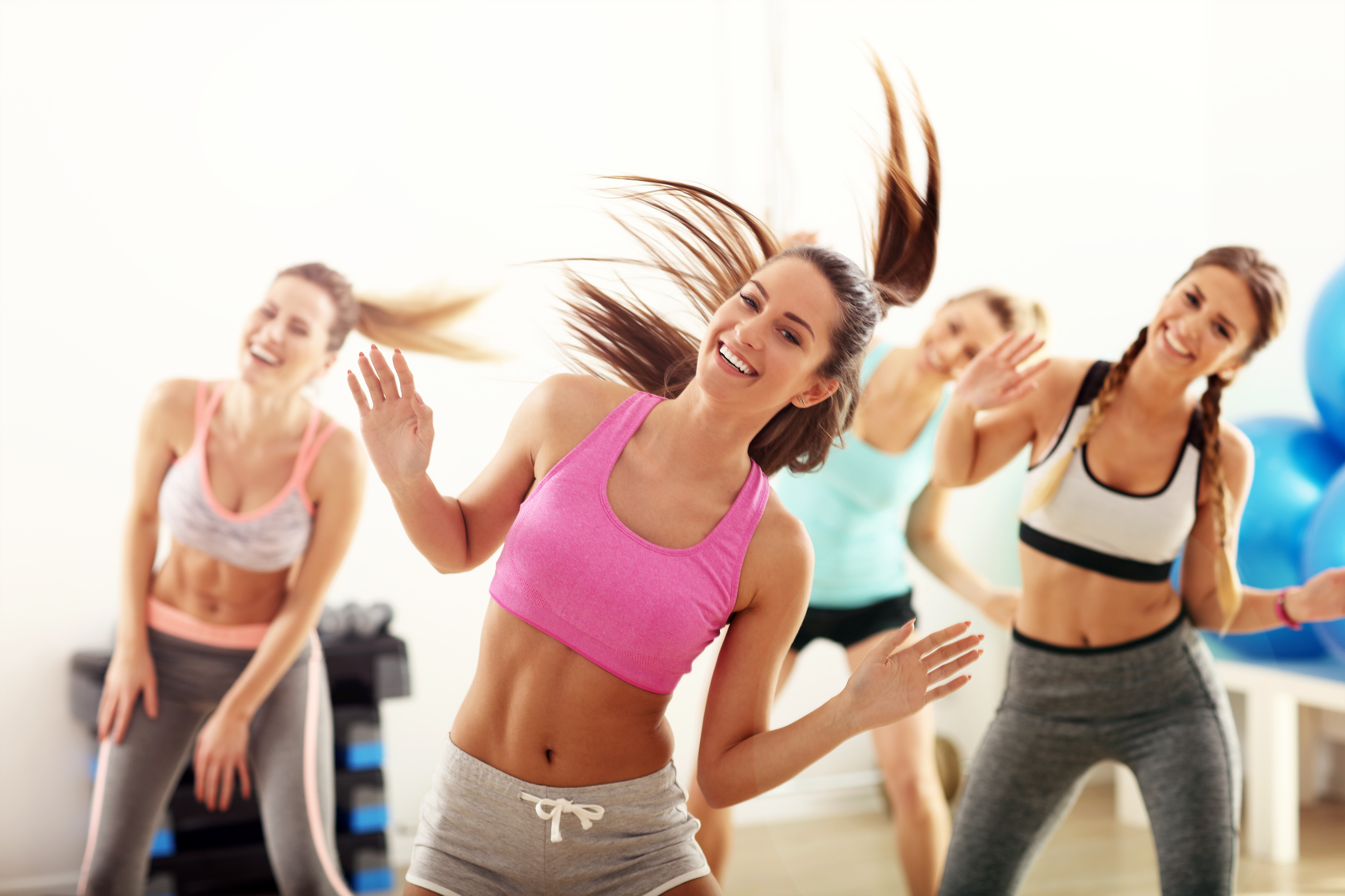 Group of energetic people with coach dancing in gym